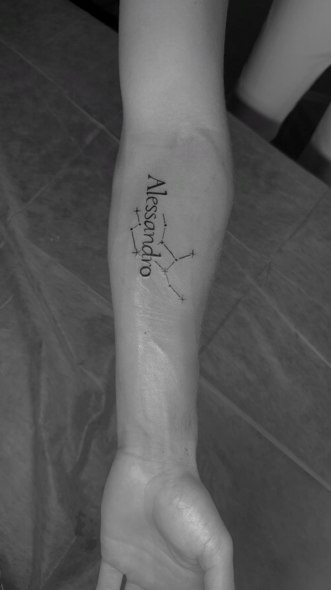 Tatouage lettering Alessandro avec constellation sur avant-bras Hakuna Tattoo Arpajon