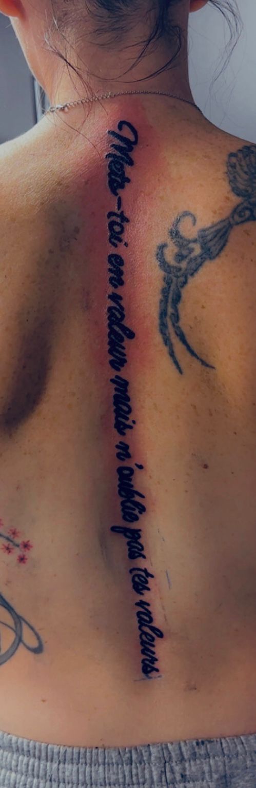 Tatouage lettering citation mets-toi en valeur le long de la colonne vertebrale Hakuna Tattoo