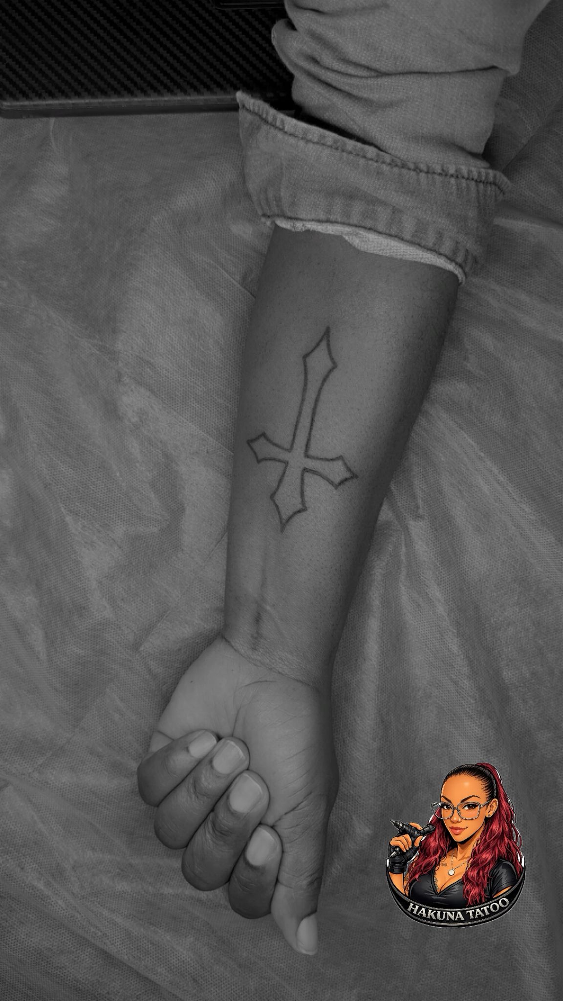 Tatouage fineline croix inversee minimaliste contour sur avant-bras Hakuna Tattoo Arpajon