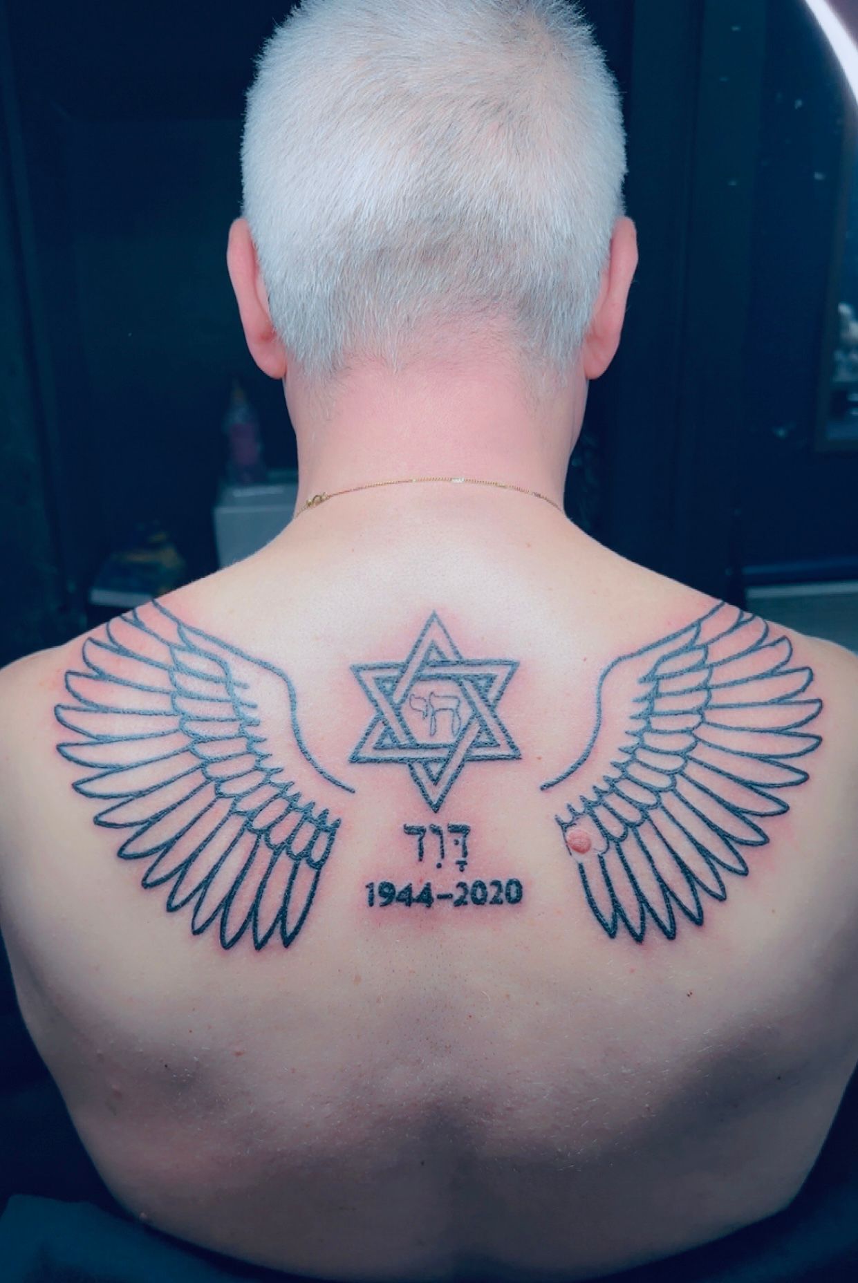 Tatouage ornemental etoile de David avec ailes et texte memorial sur le haut du dos Hakuna Tattoo