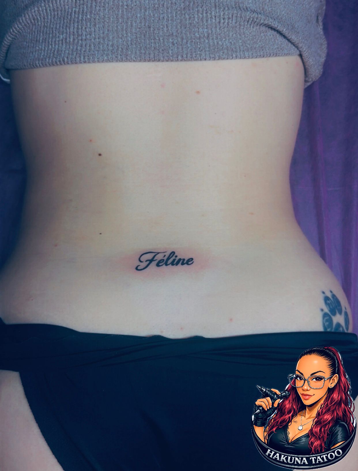 Tatouage encre rouge Feline en script cursif sur le bas du dos Hakuna Tattoo Arpajon