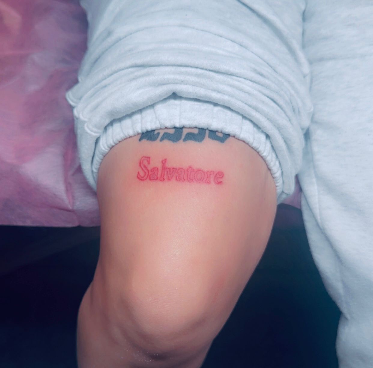 Tatouage encre rouge Salvatore en typographie gothique sur cuisse Hakuna Tattoo Arpajon