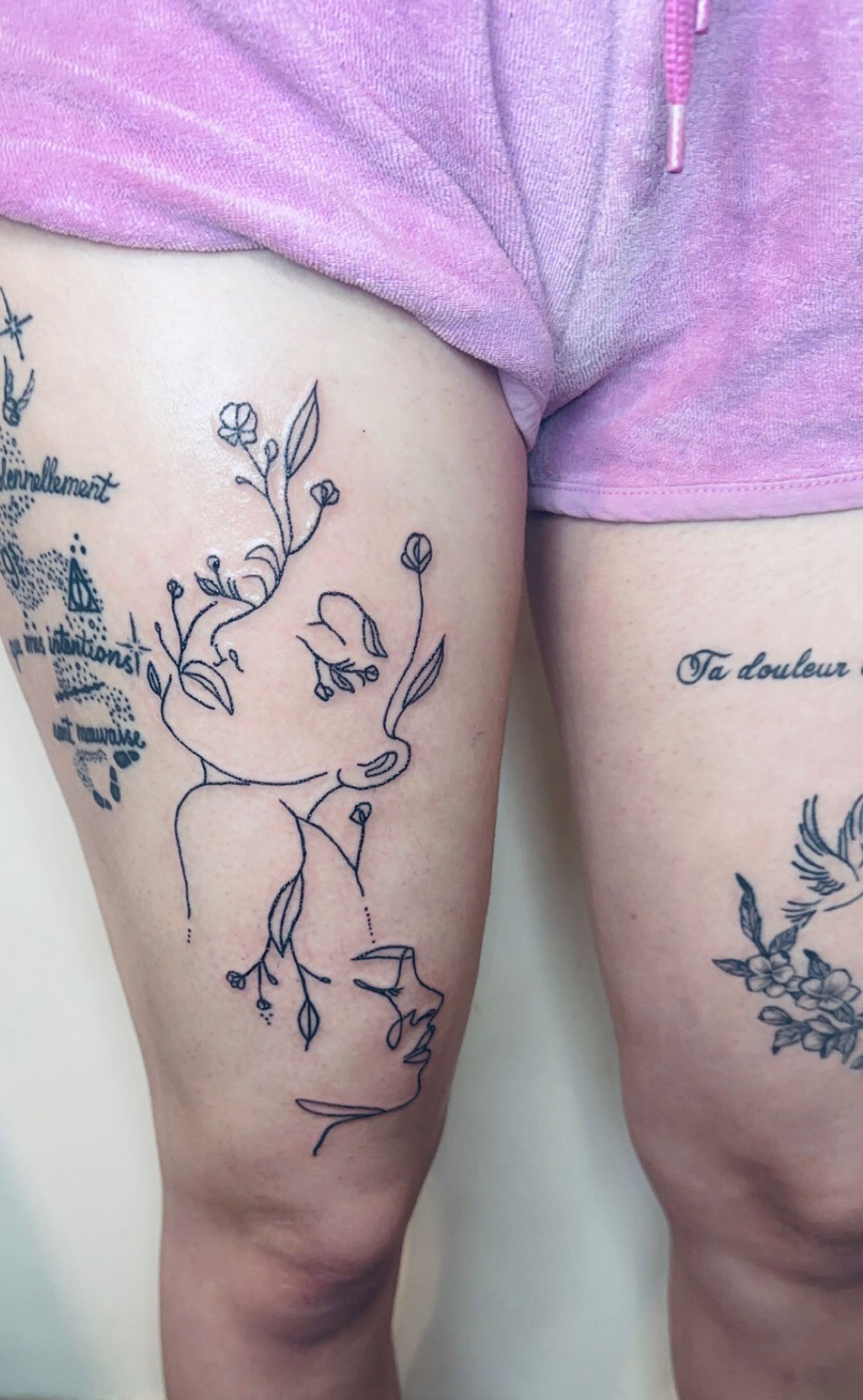 Tatouage fineline visage de femme avec composition florale lineart sur cuisse Hakuna Tattoo